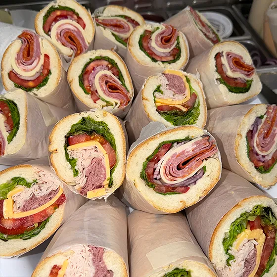 Cut deli wraps with cold cuts, lettuce, and tomato from Schmidt's catering
